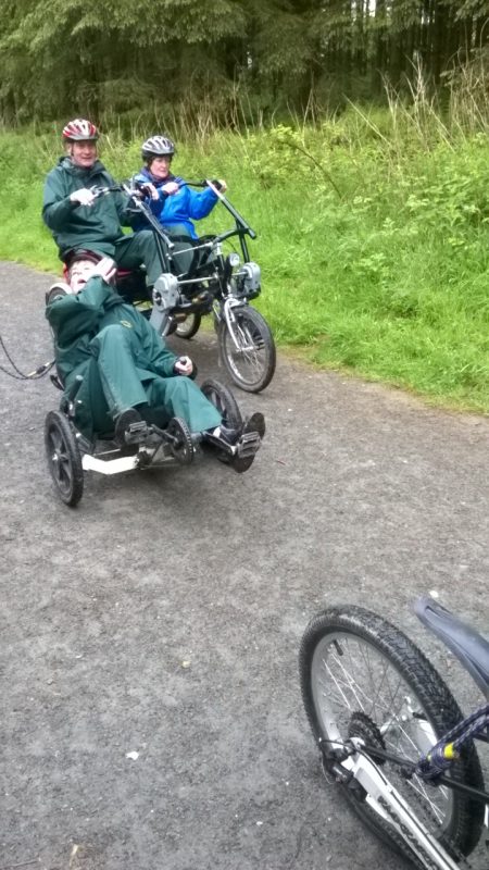 Spud and Jean and Su riding a Recumbent Bike.