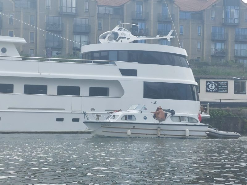 A cruise ship on the river with a helicopter on the rear deck. It is glued down as it doesn't meet the health and safety requirements